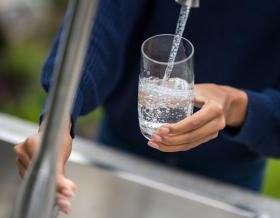 Woman's hands filling glass with water stock photo